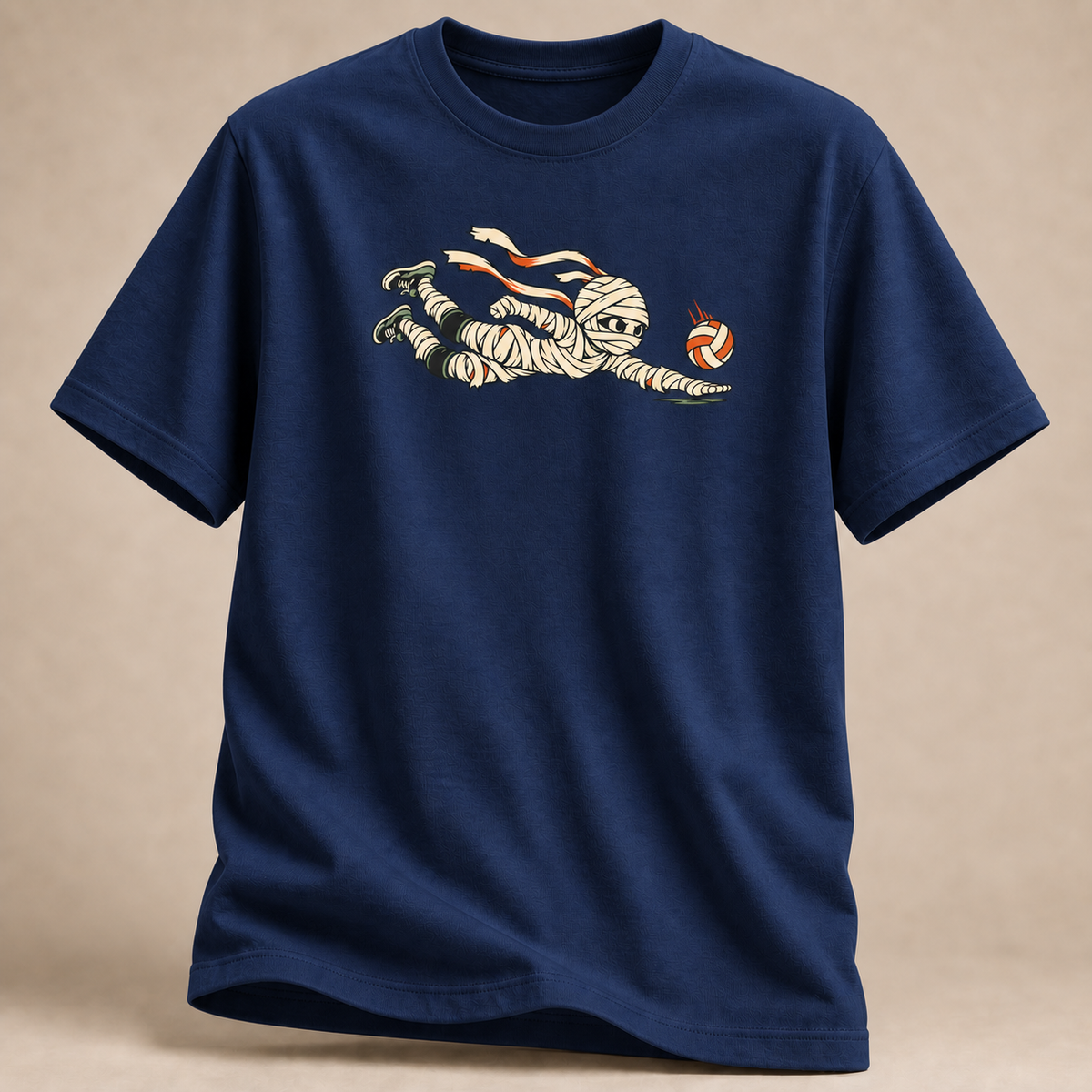 Frontansicht eines marineblauen T-Shirts: Mumie beim Hechtbagger mit Volleyball im Halloween-Motiv.