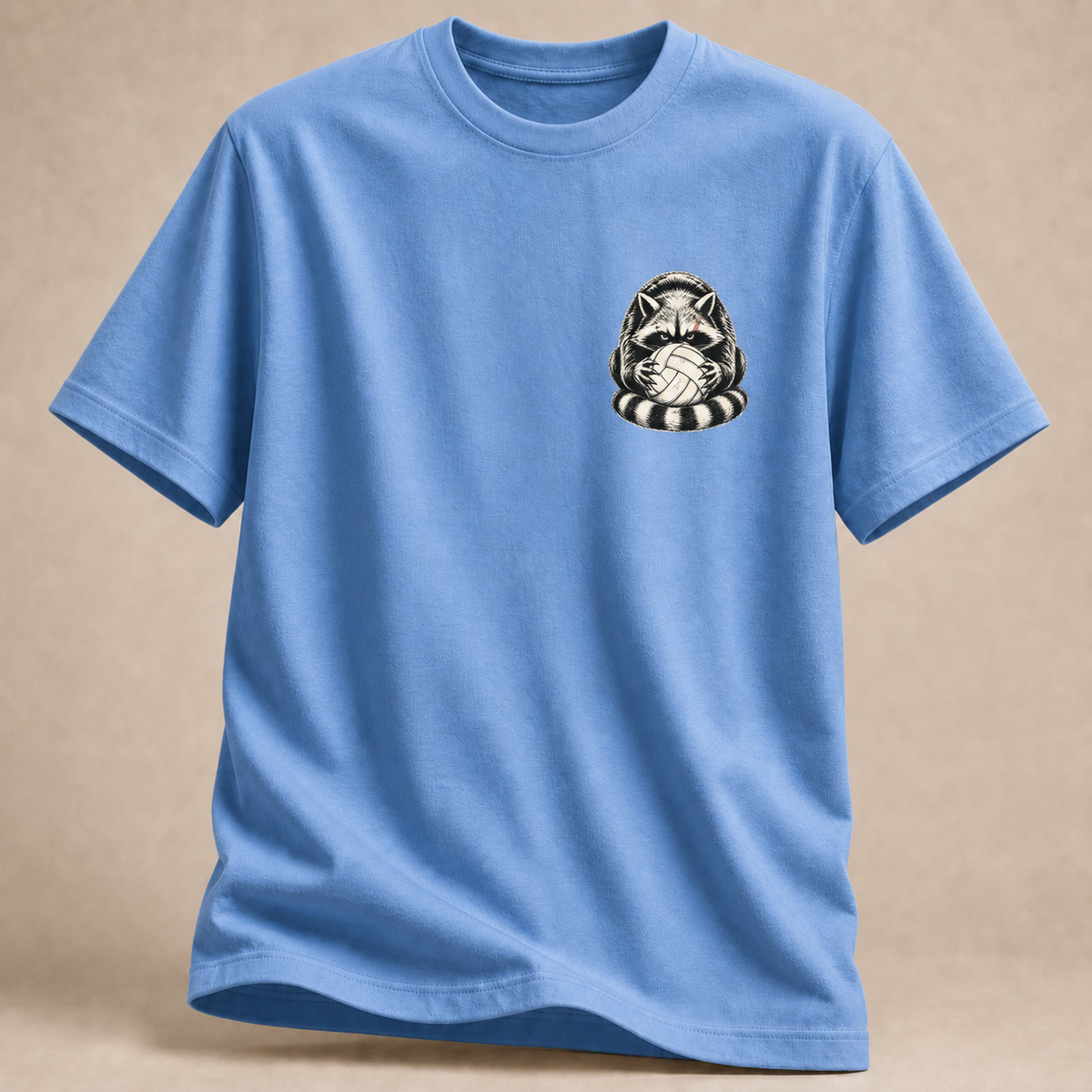 Waschbär mit Volleyball als Brustprint auf Carolina-blauem T-Shirt