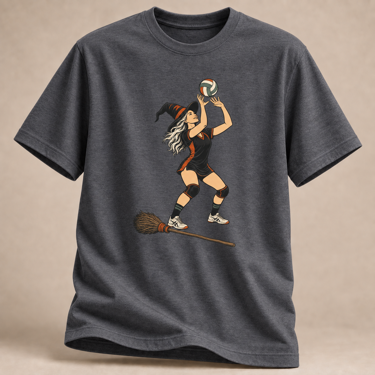 Frontansicht eines dunkelgrau melierten T-Shirts: Hexe beim Zuspiel mit Volleyball und Besen im Halloween-Motiv.