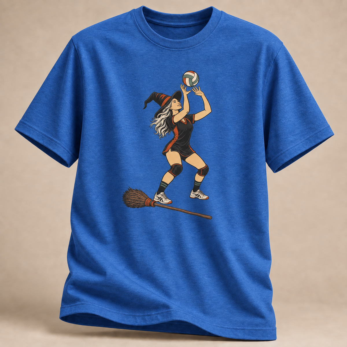 Frontansicht eines königsblau melierten T-Shirts: Hexe beim Zuspiel mit Volleyball und Besen im Halloween-Motiv.