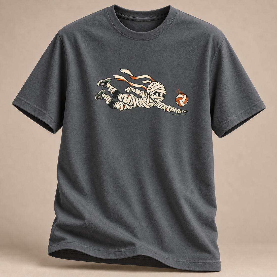 Frontansicht eines anthrazitfarbenen T-Shirts: Mumie beim Hechtbagger mit Volleyball im Halloween-Motiv.