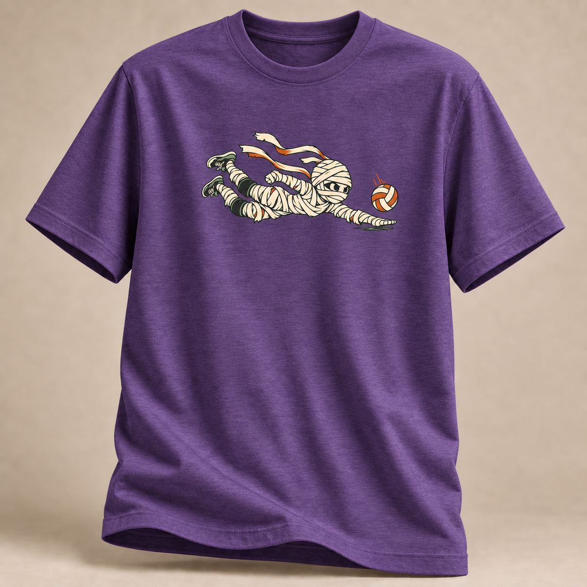 Frontansicht eines violett melierten T-Shirts: Mumie beim Hechtbagger mit Volleyball im Halloween-Motiv.