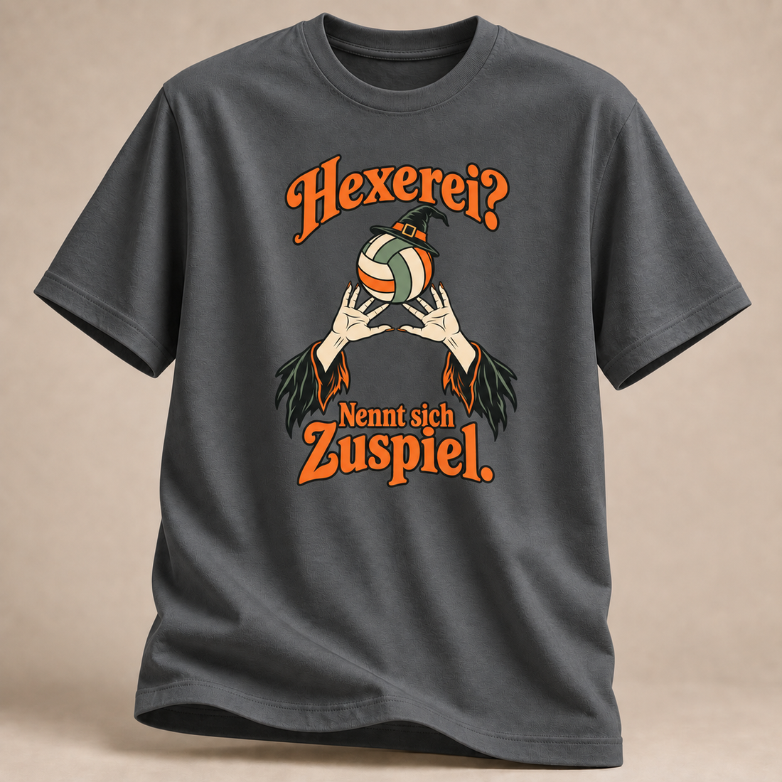 Frontansicht eines anthrazitfarbenen T-Shirts: Hexe beim Volleyball-Zuspiel.